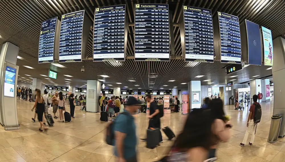  Varios pasajeros pasan por las pantallas de información en el aeropuerto Adolfo Suárez Madrid-Barajas.