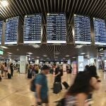  Varios pasajeros pasan por las pantallas de información en el aeropuerto Adolfo Suárez Madrid-Barajas.