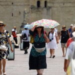 Una mujer se cubre del sol con una sombrilla en el Puente Romano de Córdoba