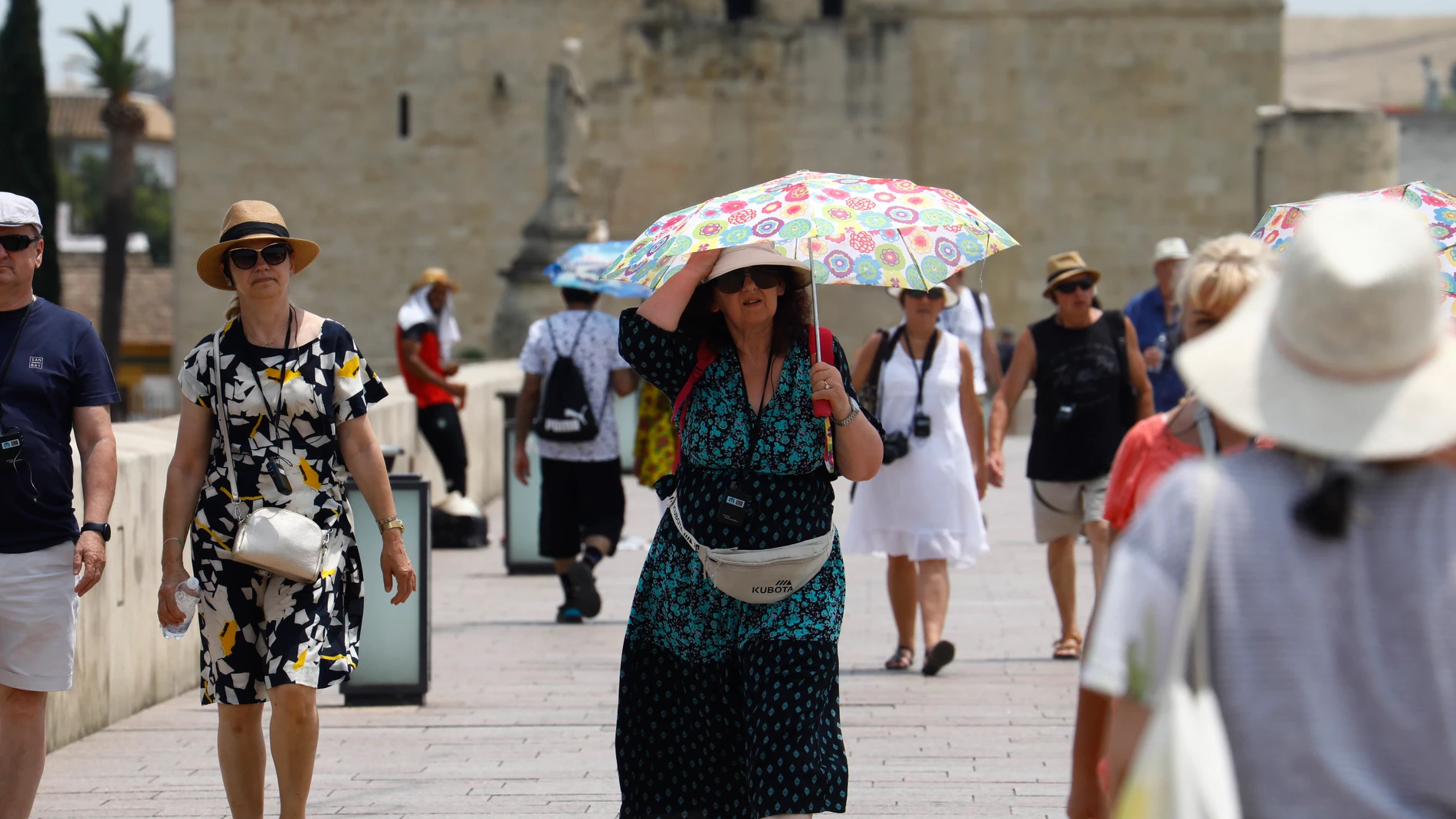 Una mujer se cubre del sol con una sombrilla en el Puente Romano de Córdoba