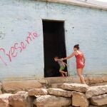 Una mujer y un niño entran a una casa marcada con un grafiti del grupo guerrillero del ELN en Cúcuta (Colombia)