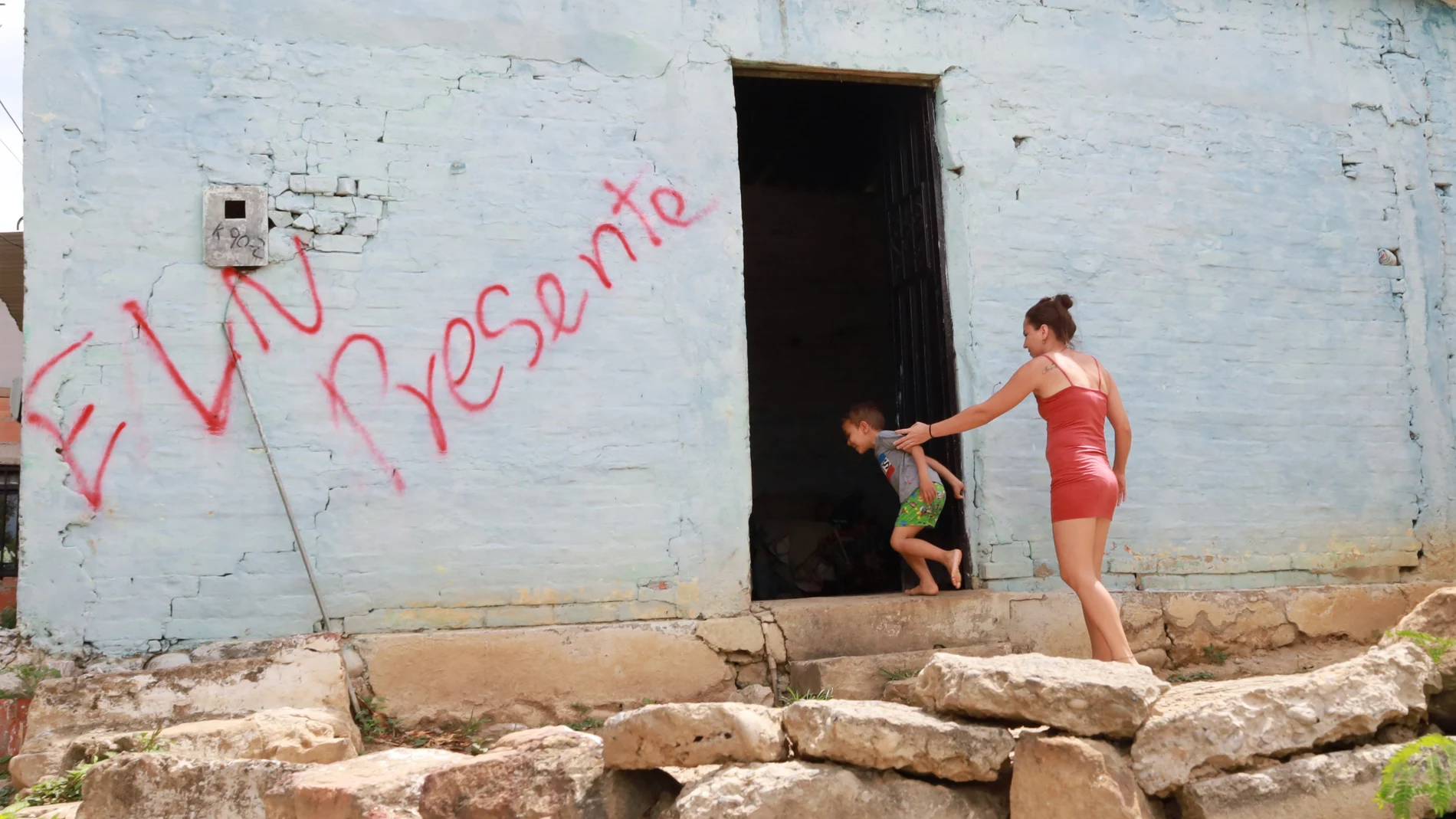 Una mujer y un niño entran a una casa marcada con un grafiti del grupo guerrillero del ELN en Cúcuta (Colombia)