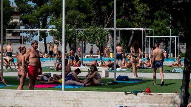Varias personas disfrutan y se relajan este domingo en una piscina municipal en La Elipa, intentando paliar la ola de calor de esta jornada de julio. 