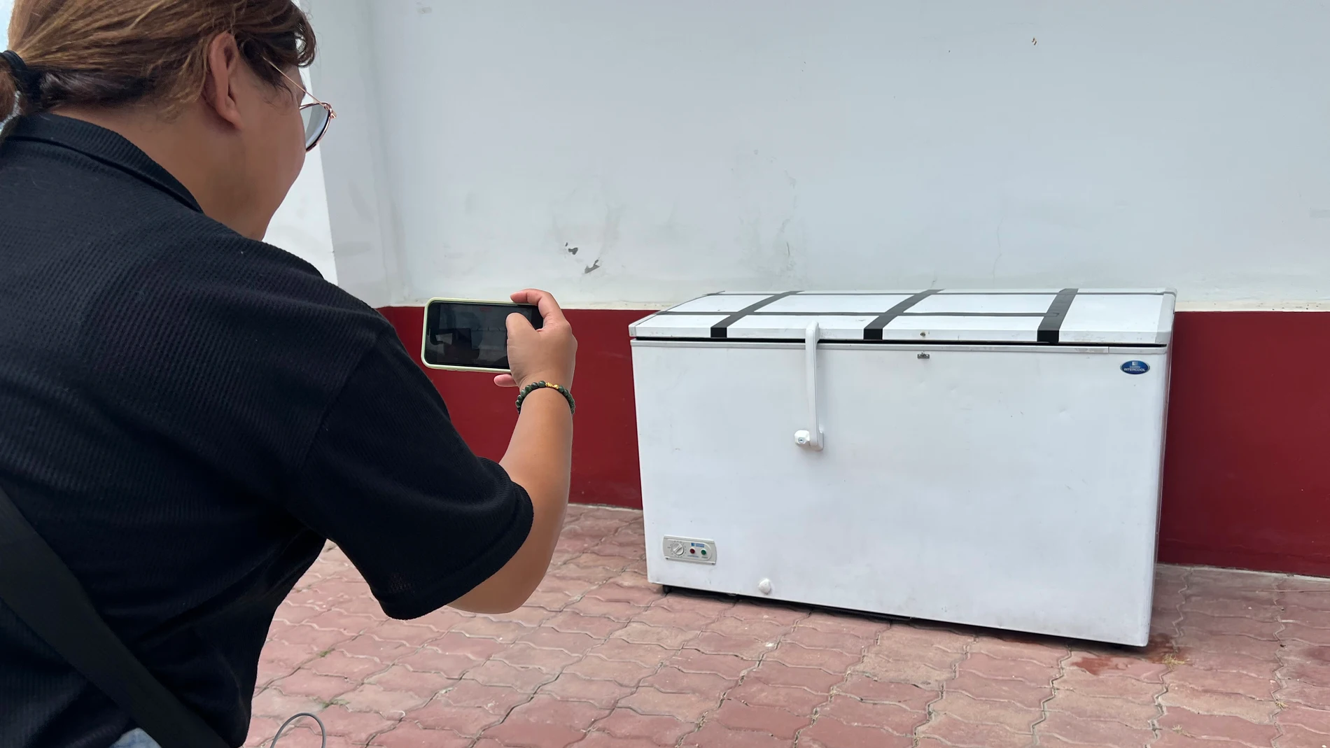 A Thai reporter takes a photo of an empty freezer at the Nong Prue police station in Pattaya, Chonburi province, Thailand, Tuesday, July 11, 2023. The dismembered body of a 62-year-old German businessman Hans-Peter Mack who has been missing for a week has been found in the freezer of a house in southern Thailand, police said Tuesday. (AP Photo)