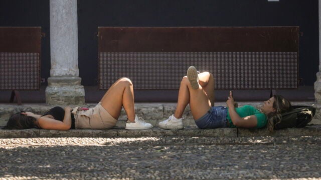  Dos turistas descansan a la sombra en el Patio de los Naranjos de la Mezquita-Catedral de Córdoba