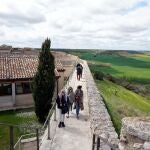 Turistas recorren las murallas de la localidad vallisoletana de Urueña, la Villa del Libro