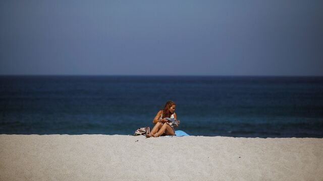 Una mujer toma el sol en la coruñesa playa de Riazor.