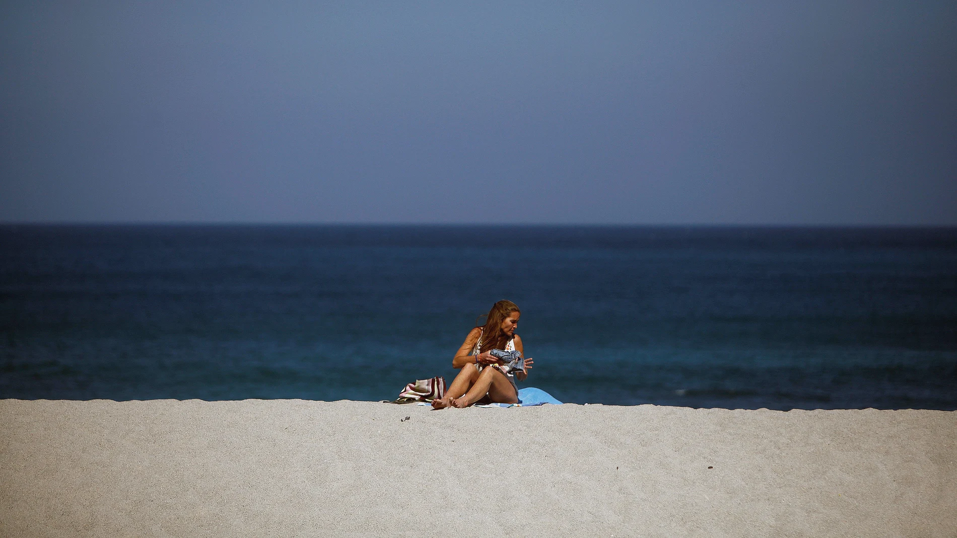 Una mujer toma el sol en la coruñesa playa de Riazor.