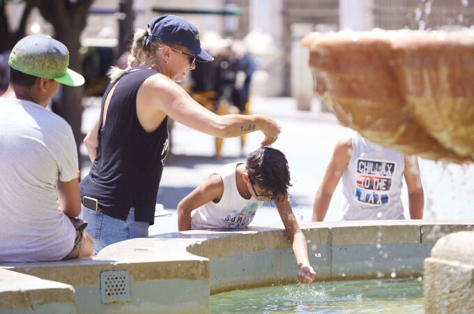 Un niño se refresca este martes en una fuente en Murcia. Las temperaturas se prevé que subirán aún más mañana miércoles en el día álgido de la ola de calor con termómetros que llegarán a 44 grados
