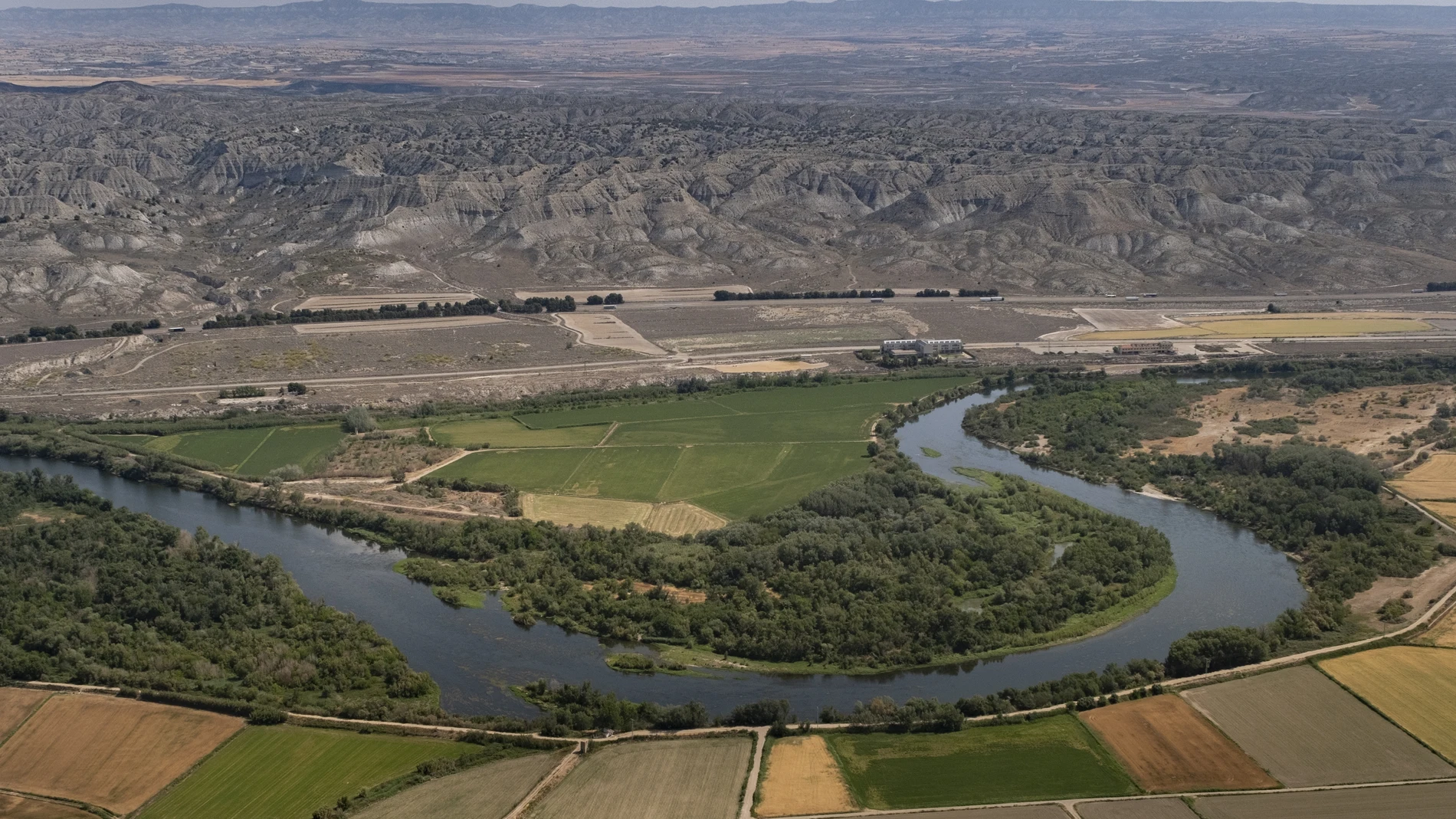 Cultivos de regadío intensivo en torno a un meandro del río Ebro a su paso por Osera de Ebro, en Zaragoza. Al fondo, el desierto de los Monegros.