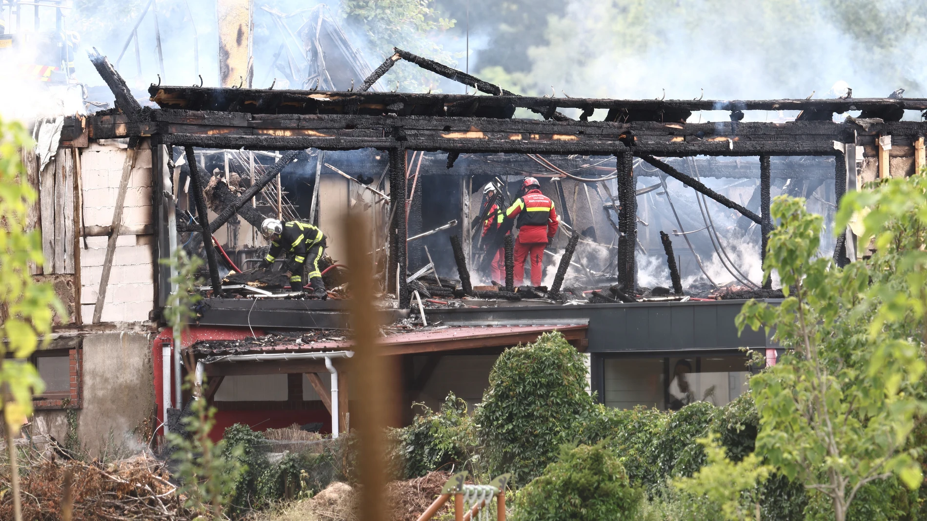 Los bomberos inspeccionan un edificio quemado después de que se produjera un incendio en un centro de vacaciones para discapacitados en Wintzenheim, al este de Francia, el 9 de agosto de 2023.