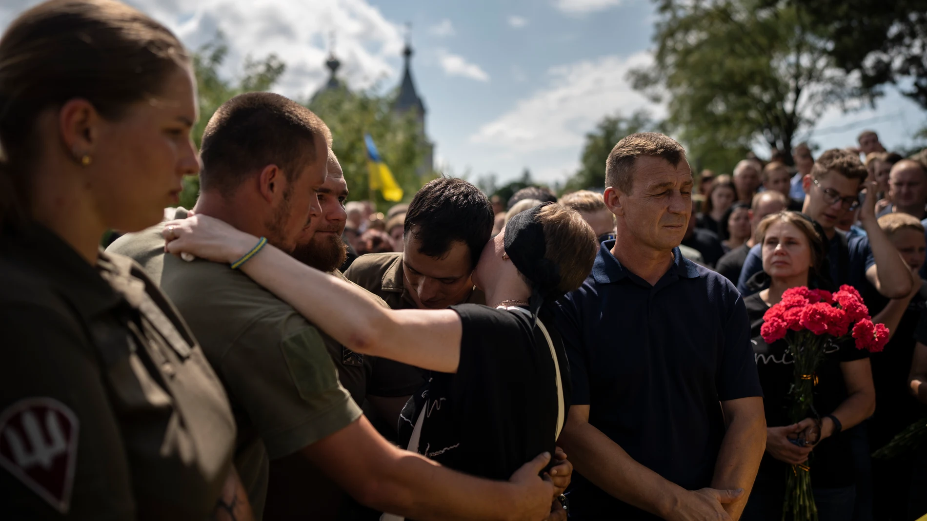 Oleksander Mykhailenko's mother, Svitlana, kisses her son's colleagues at his funeral in Zhukin, Ukraine, Friday, Aug. 11, 2023. Oleksander, a soldier in the Ukrainian army, died in battle in the Kharkiv region in March this year but his body was only identified recently. (AP Photo/Bram Janssen)