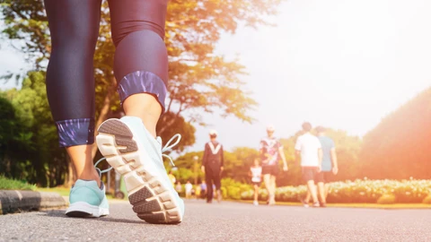 Mujer fitness joven caminando con un grupo de personas haciendo ejercicio caminando en el parque.
