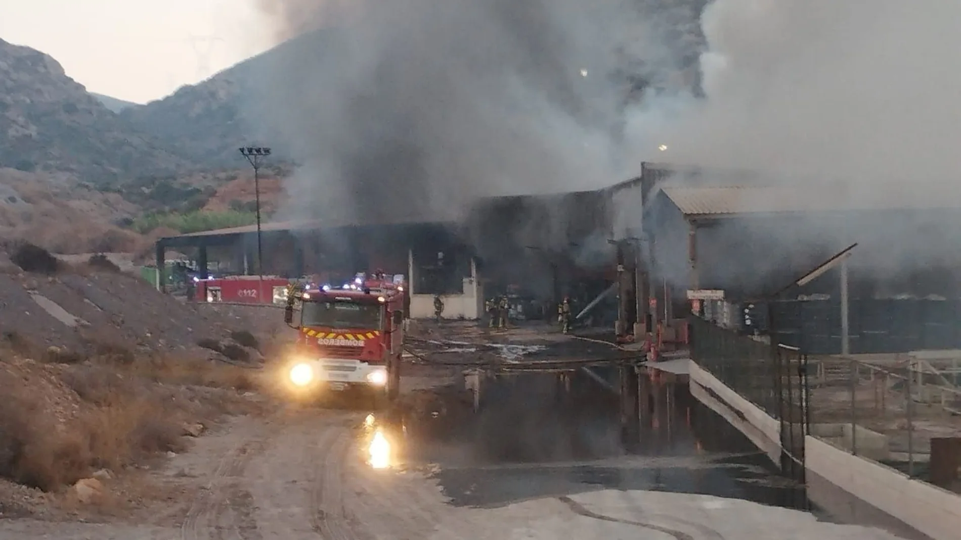 Bomberos trabajan en las labores de extinción de un incendio en una nave de gestión de residuos en Escombreras