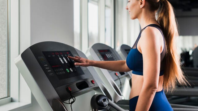 Un mujer entrena en una cinta de correr en un gimnasio