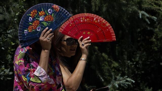 Dos mujeres se protegen del sol con abanicos en El Retiro