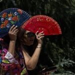 Dos mujeres se protegen del sol con abanicos en El Retiro