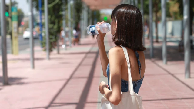 Una joven bebe agua para refrescarse en Sevilla (Andalucía, España)