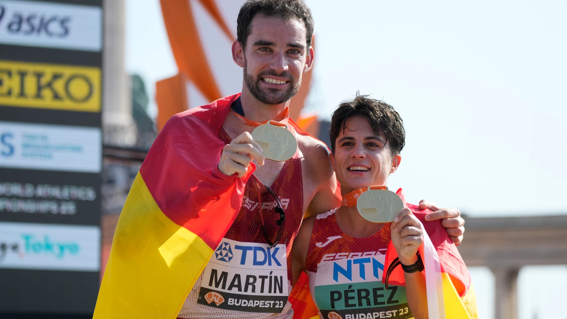 Alvaro Martin, of Spain, and his compatriot María Perez show their gold medals after winning the men's and women's 35-kilometer race walk during the World Athletics Championships in Budapest, Hungary, Thursday, Aug. 24, 2023. (AP Photo/Ashley Landis)