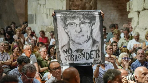 CODALET, (FRANCIA), 21/08/2023.-Un asistente sostiene una pancarta con la cara de Carles Puigdemont y la frase "No Surrender" este lunes en la abadía de Sant Miquel de Cuixà, en Codalet (Francia), durante el acto homenaje al músico Pau Casals con motivo de los 50 años de su muerte, al que el expresidente de la Generalitat también ha asistido. EFE/David Borrat