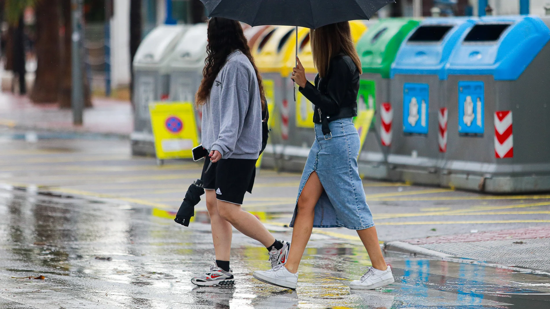 Dos chicas caminan por la calle bajo un paraguas