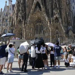 Varios turistas equipados con sombrillas visitan la Sagrada Familia, en Barcelona.
