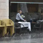 Un camarero recoge una mesa en una terraza 