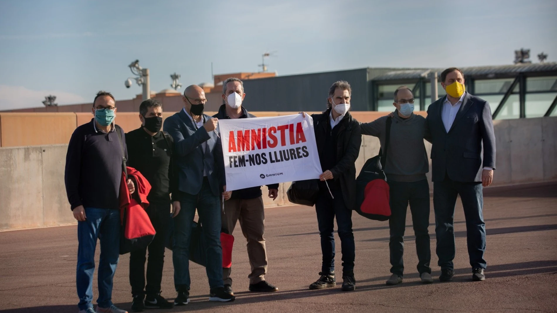 (I-D) El exconseller de Territorio y Sostenibilidad de la Generalitat Josep Rull; el expresidente de la ANC y exdiputado de JxCat, Jordi Sànchez; el exconseller Raül Romeva; el exconseller de Interior de la Generalitat Quim Forn; el presidente de Òmnium Cultural, Jordi Cuixart; el exconseller de JxCat Jordi Turull; el líder de ERC y exvicepresidente del Govern, Oriol Junqueras, sostienen una pancarta donde se puede leer "Amnistia Fem-nos lliures (Amnistía. Hagámonos libres), a su salida de la cárcel de Lledoners donde cumplían condena por el 1-O.