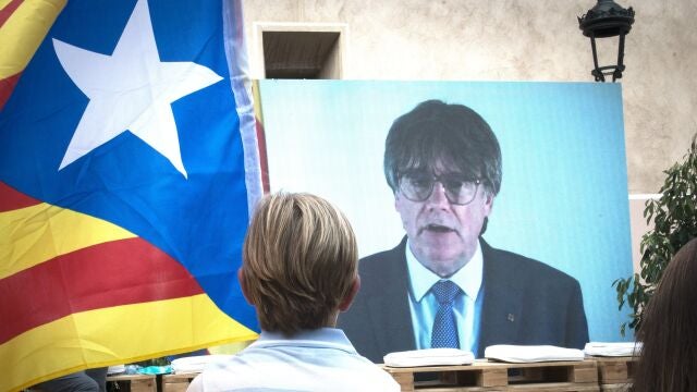Un niño observa la intervención telemática de Puigdemont en el mitin central del partido JxCAT, en Amer, Girona.