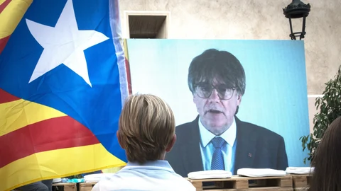 Un niño observa la intervención telemática de Puigdemont en el mitin central del partido JxCAT, en Amer, Girona.