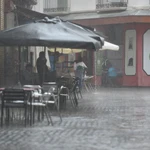 Varias personas se protegen de la lluvia en una terraza en Huesca