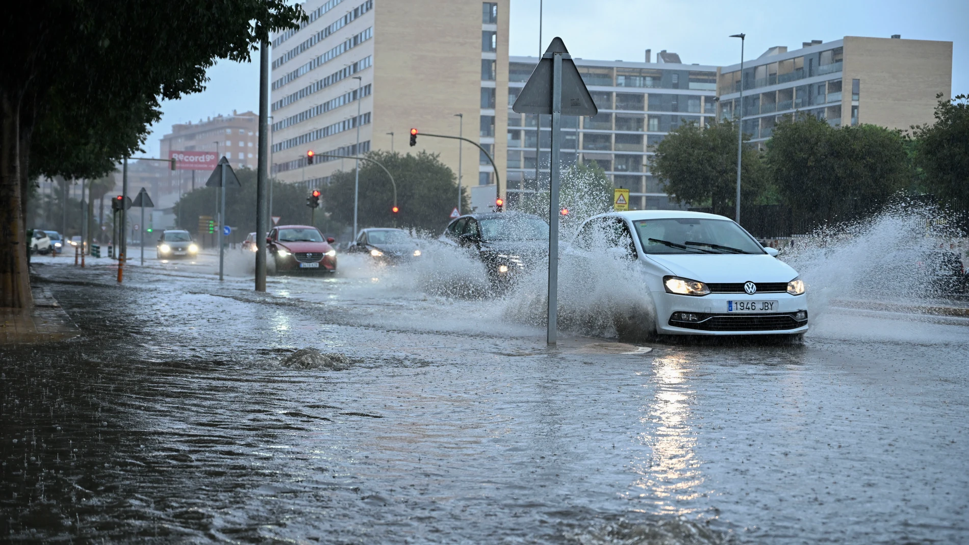 Varios vehículos transitan por la avenida Casalduch parcialmente inundada este sábado en Castellón de la Plana