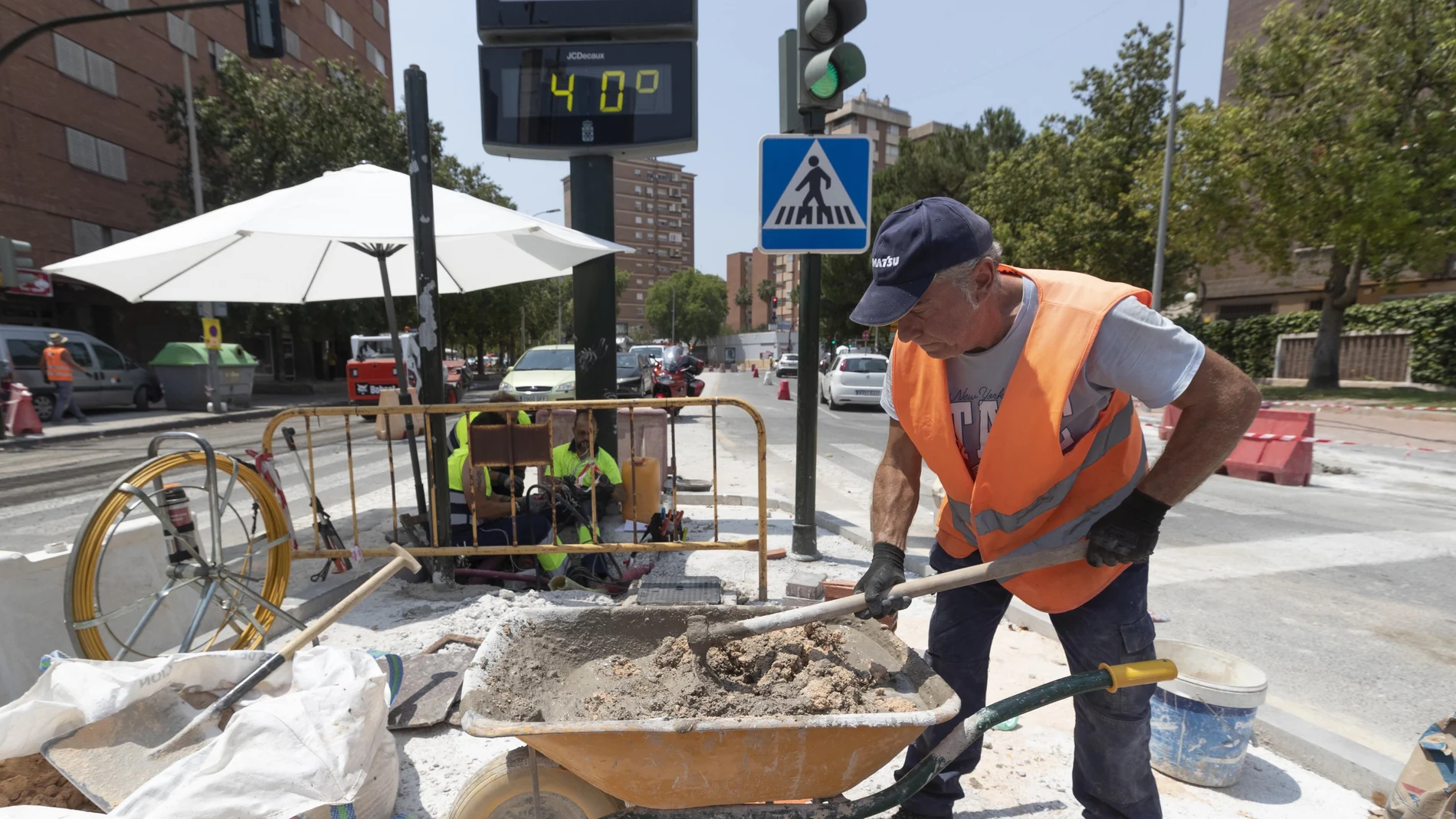 Un trabajador de la construcción junto a un termómetro que marca cuarenta grados este martes en la avenida de la Fama de Murcia. 