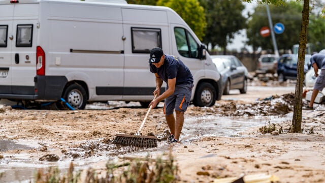 Una persona trata de evitar que el agua se acumule en una de las zonas afectadas por las inundaciones provocadas por la DANA este lunes en El Álamo, Madrid (España)