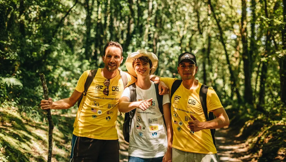 Ignacio Campo (izquierda) y Javier Díaz (derecha) de la Fundación International Studies posan junto a Nicolás García, estudiante de secundaria de Consuegra, en un sendero boscoso que forma parte del Camino de Santiago. Nicolás ha participado en el programa Go! American English, colaboración entre la Embajada de Estados Unidos y la CIS University en Madrid. Julio de 2023. 