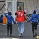 Una voluntaria de la Cruz Roja acompaña a dos menores migrantes en Canarias