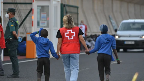 Una voluntaria de la Cruz Roja acompaña a dos menores migrantes en Canarias
