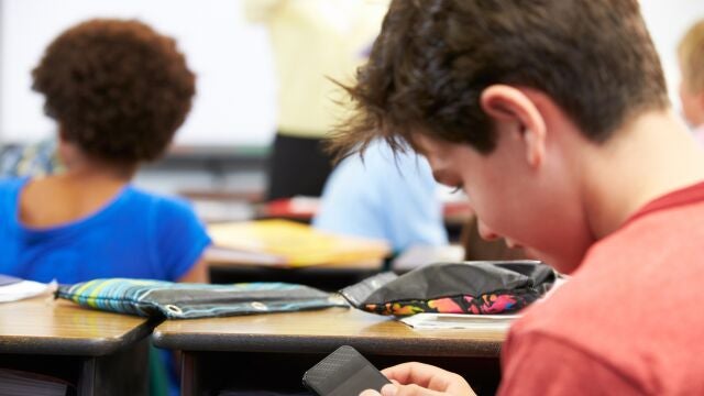 Niño con teléfono móvil en el colegio.