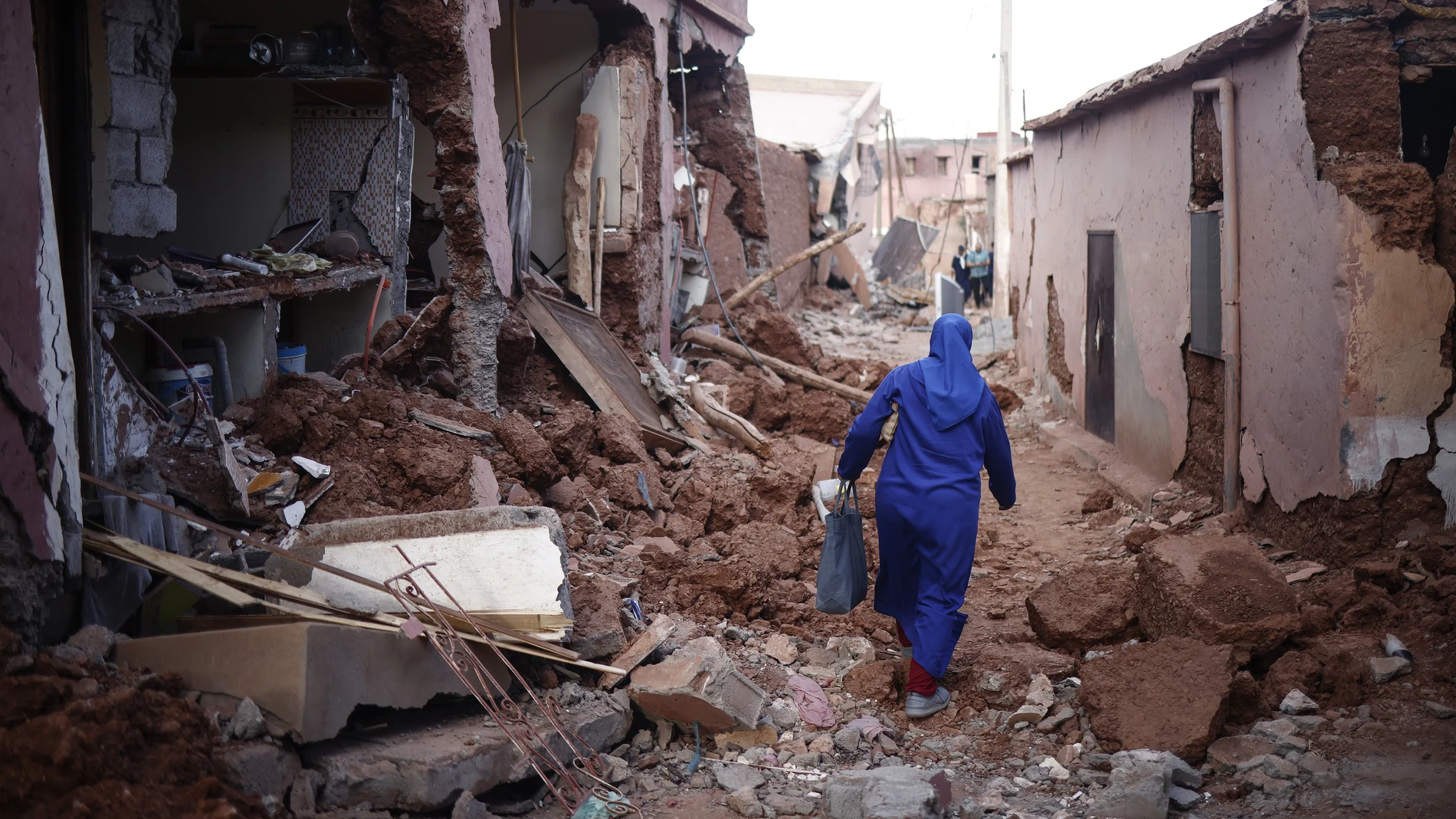 Ouirgane (Morocco), 10/09/2023.- A woman passes by damaged buildings following a powerful earthquake in Ouirgane, south of Marrakesh, Morocco, 10 September 2023. A magnitude 6.8 earthquake that struck central Morocco late 08 September has killed at least 2,012 people and injured 2,059 others, 1,404 of whom are in serious condition, damaging buildings from villages and towns in the Atlas Mountains to Marrakesh, according to a report released by the country's Interior Ministry. The earthquake has affected more than 300,000 people in Marrakesh and its outskirts, the UN Office for the Coordination of Humanitarian Affairs (OCHA) said. (Terremoto/sismo, Marruecos) EFE/EPA/YOAN VALAT
