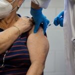 Una enfermera pone una vacuna a una mujer mayor