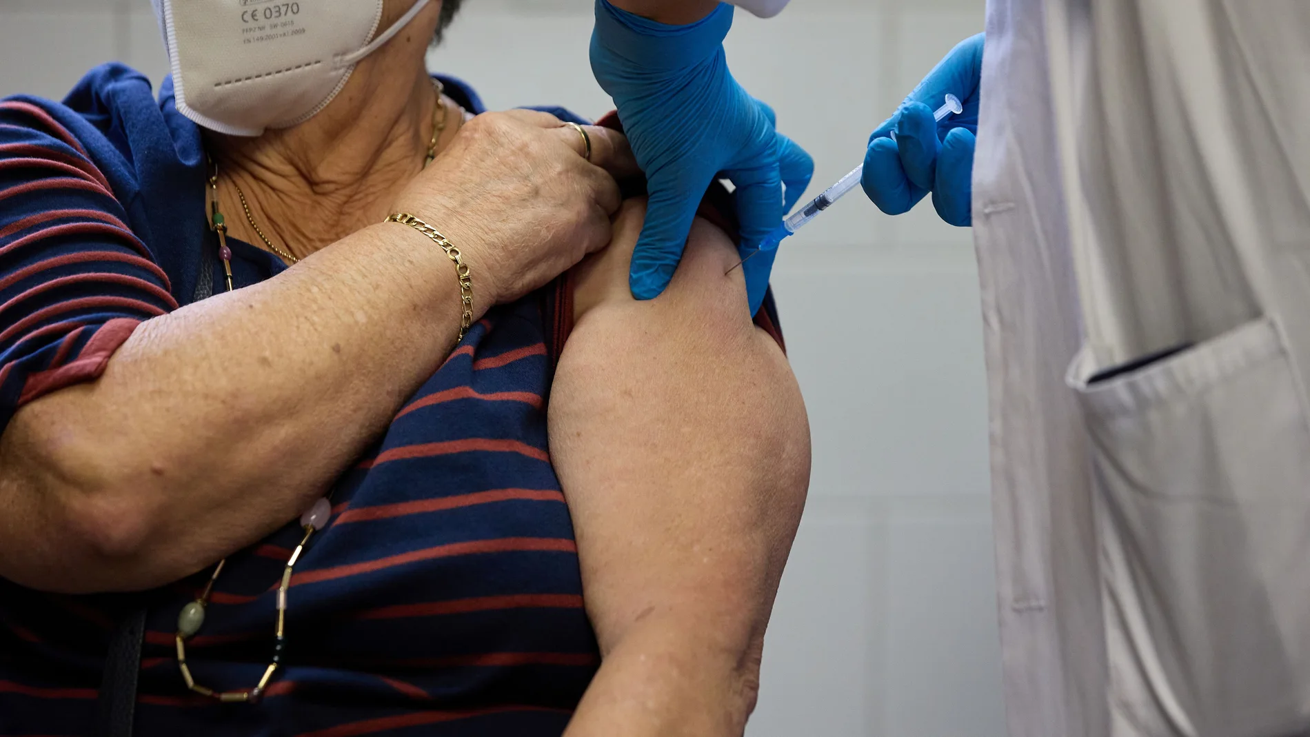 Una enfermera pone una vacuna a una mujer mayor