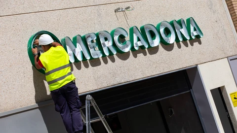 Dos operarios colocan el cartel luminoso de Mercadona en la fachada de una tienda. © Jesús G. Feria.