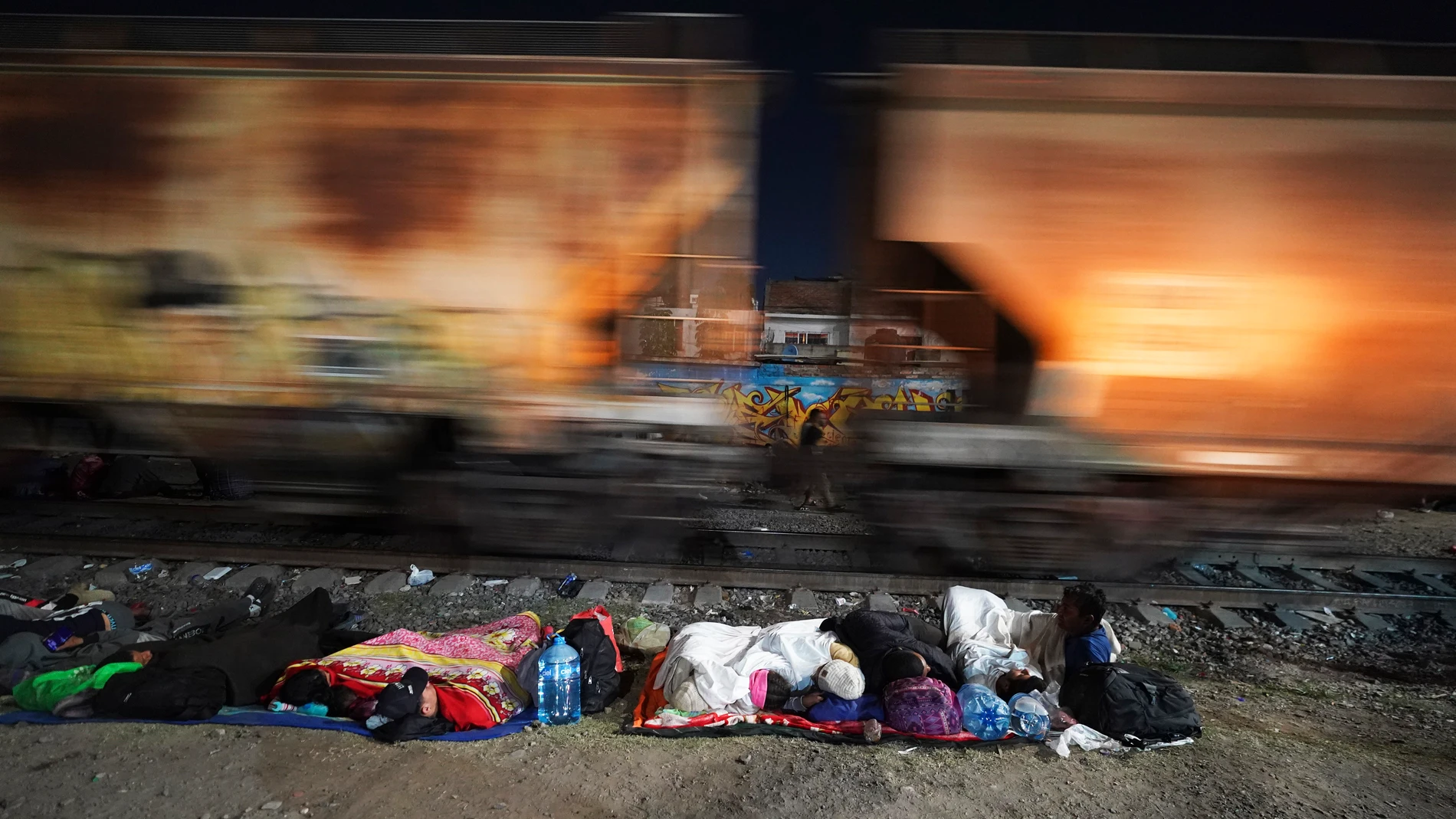 Migrants sleep alongside a railroad track as they wait for a northbound freight train that stops long enough for them to hop, in Irapuato, Mexico, Friday, Sept. 22, 2023. (AP Photo/Marco Ugarte)
