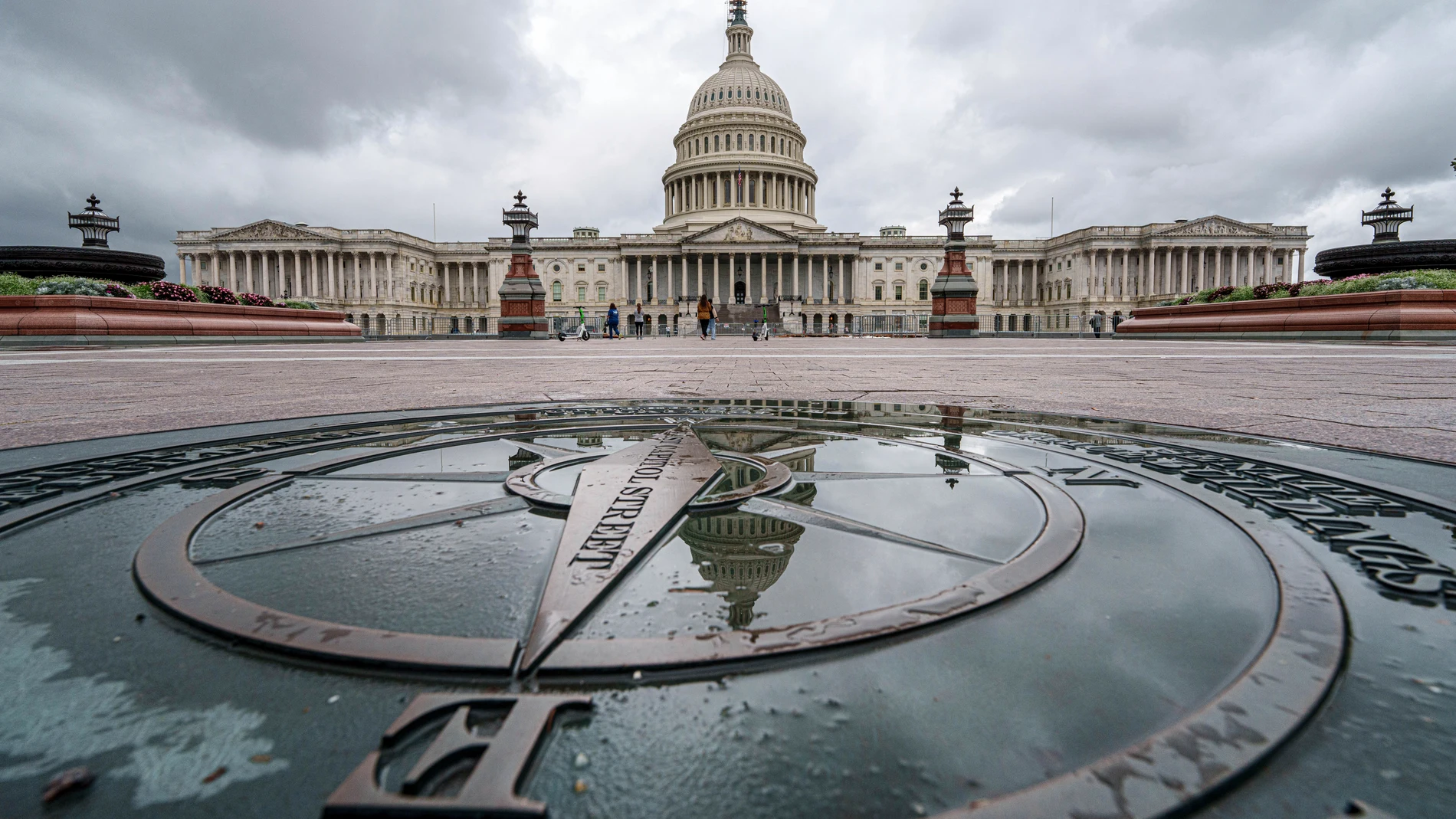 The U.S. Capitol Dome is reflected in a rain puddle on the compass star on the east side of the building, Sunday, Sept. 24, 2023. Congress will return this week to continue debating a temporary funding bill to keep the government open and running. (AP Photo/J. David Ake)
