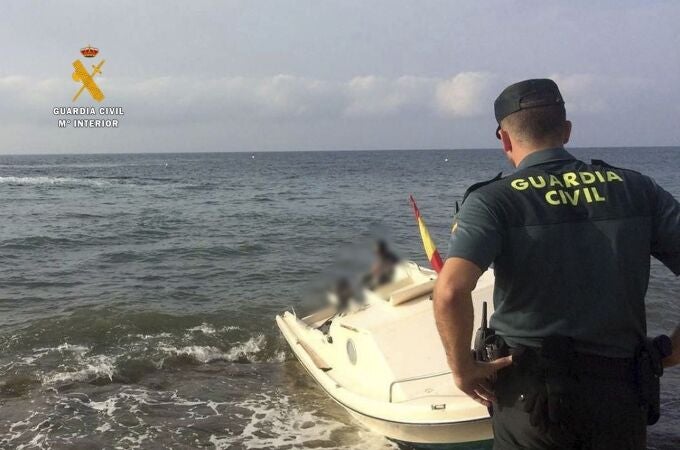 Un agente de la Guardia Civil frente a una patera-taxi que llegó al litoral de Carboneras (Almería)