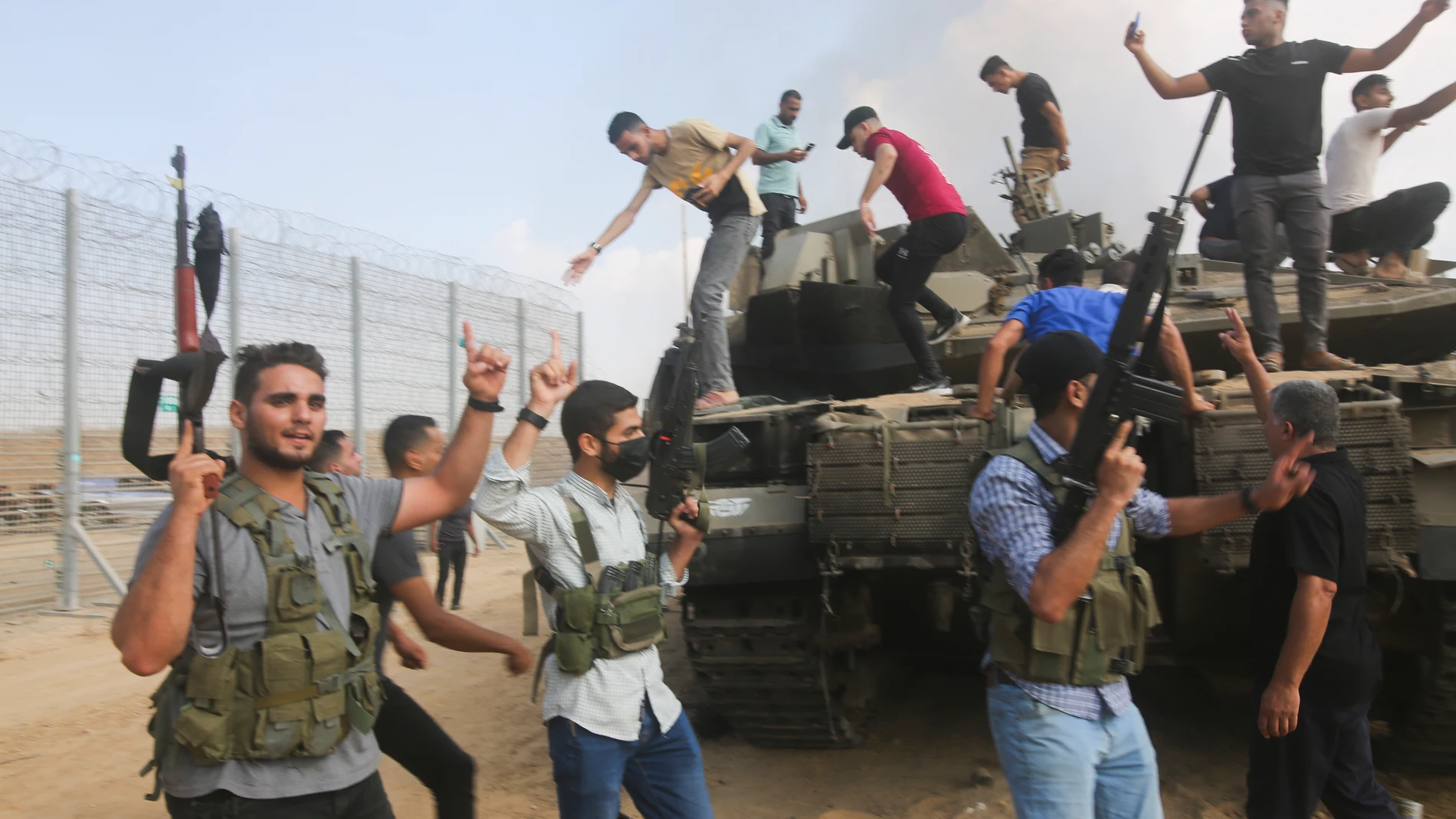 Palestinian militants celebrate by an Israeli tank at the border fence of the Gaza Strip on Saturday, Oct. 7, 2023. The militant Hamas rulers of the Gaza Strip carried out an unprecedented, multi-front attack on Israel at daybreak Saturday, firing thousands of rockets as dozens of Hamas fighters infiltrated the heavily fortified border in several locations by air, land, and sea and catching the country off-guard on a major holiday. (AP Photo/Hatem Ali)
