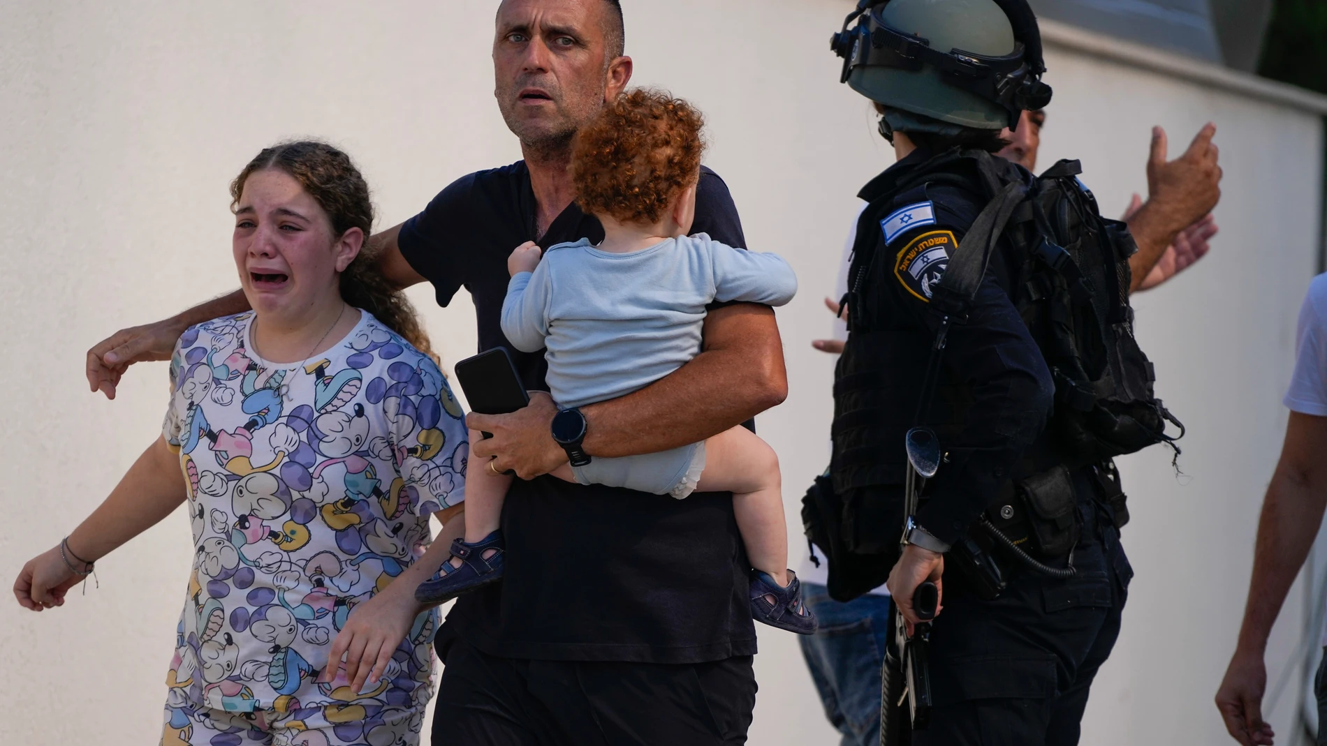 FILE - Israeli police officers evacuate a family from a site hit by a rocket fired from the Gaza Strip, in Ashkelon, southern Israel, Saturday, Oct. 7, 2023. The rockets were fired as Hamas announced a new operation against Israel. (AP Photo/Tsafrir Abayov, File)