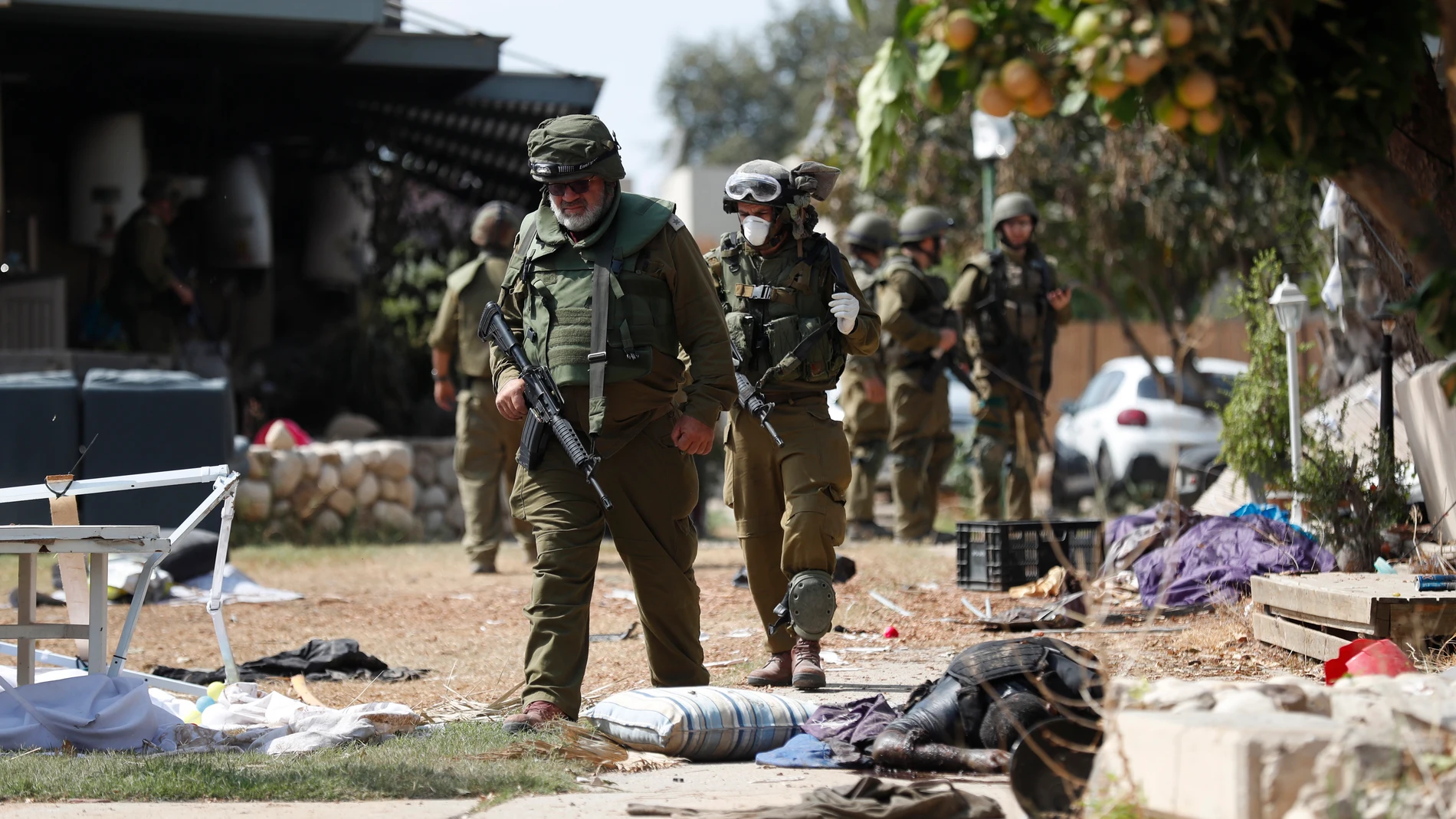 Kfar Aza (Israel), 10/10/2023.- Israeli soldiers walk next to the body of Hamas militant killed in Kfar Aza kibbutz next to the border with Gaza, 10 October 2023. More than 900 people have been killed, around 150 were taken as hostages, and 1,500 others injured, according to Israel Defence Forces (IDF), after the Islamist movement Hamas launched an attack against Israel on 07 October. More than 3,000 people, including 1,500 militants from Hamas, have been killed and thousands injured in Gaza ...