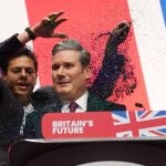 A protester throws glitter over and disrupts (L) British Labour leader Keir Starmer during his keynote speech at the Labour Party Conference in Liverpool.