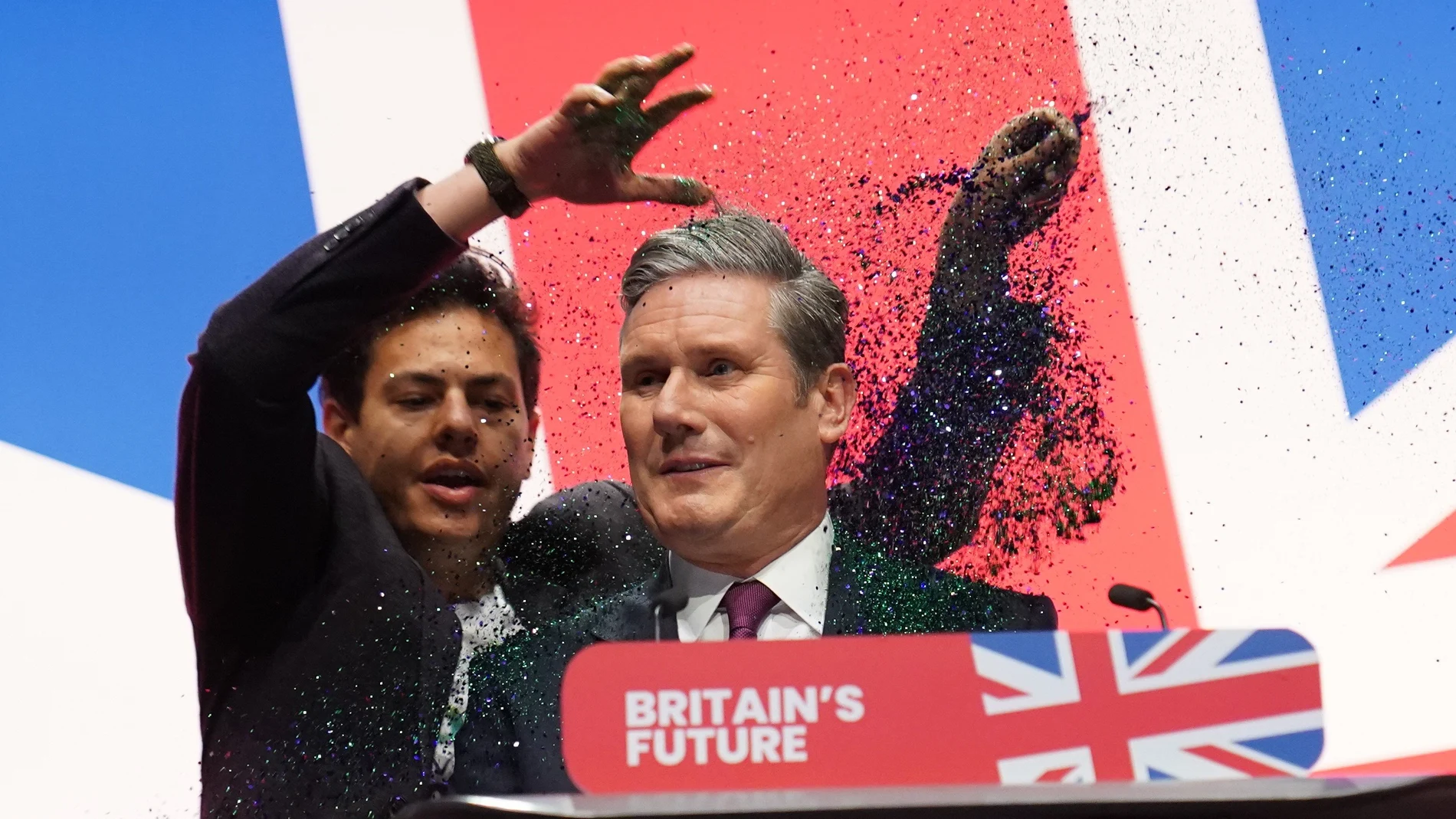A protester throws glitter over and disrupts (L) British Labour leader Keir Starmer during his keynote speech at the Labour Party Conference in Liverpool.